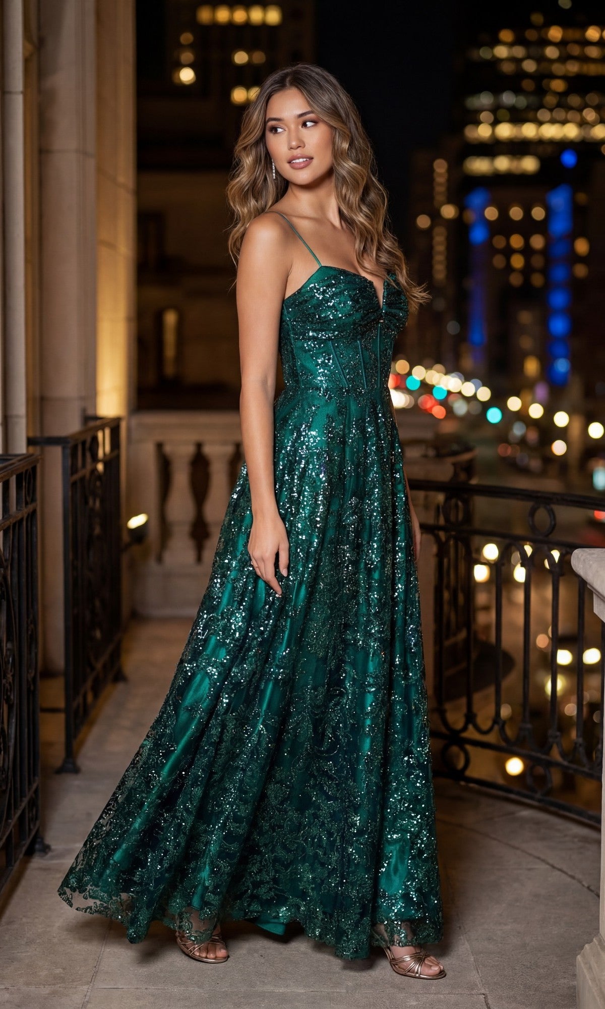 A woman wearing the teal Long Glitter Prom Dress: Blondie Nites 5409BN stands on a balcony at night, city lights blurred in the background.